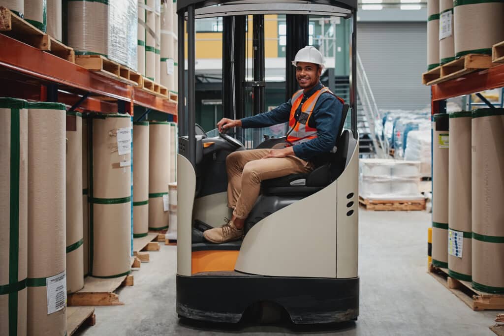 Forklift driver sitting in machine transporting goods